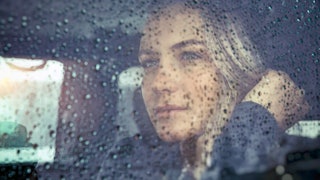 Sad divorced woman sitting in a car looking out the window
