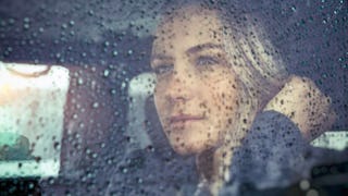 Sad divorced woman sitting in a car looking out the window