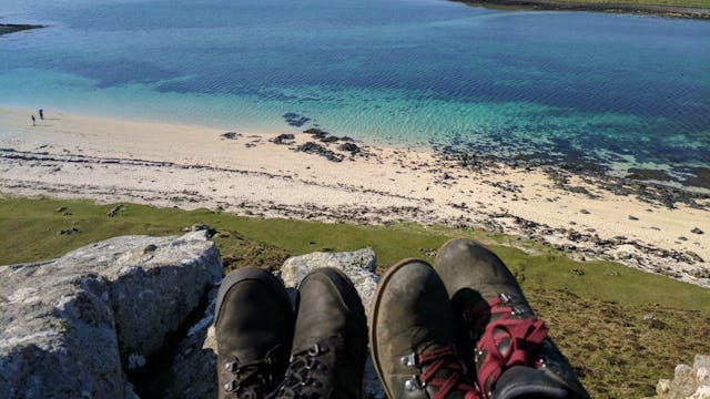 Two pairs of shoes that belong to parents that are on a child-free vecation with a view of the beach...