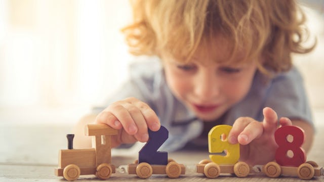 A toddler boy playing with a train toy with numbers on top