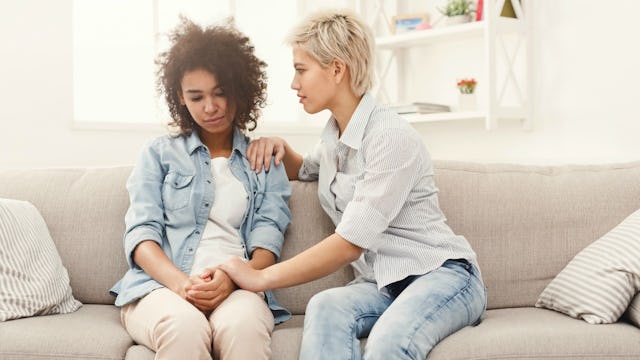A lady sitting on the couch comforting her friend going through a divorce