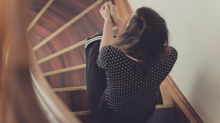 A woman sitting on the staircase thinking about how she needs her mom 