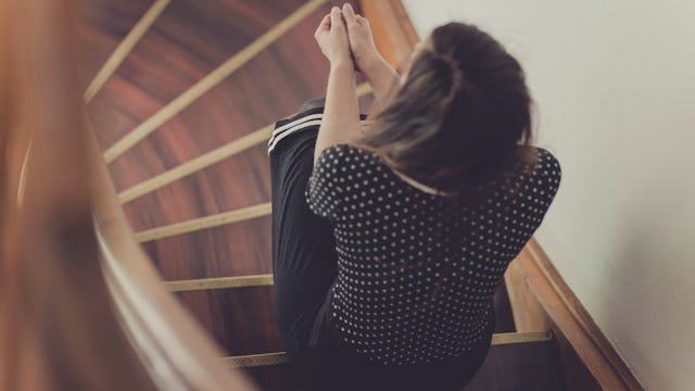 A woman sitting on the staircase thinking about how she needs her mom
