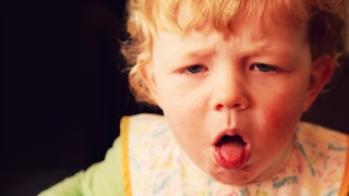 A blonde-haired baby coughing/chocking