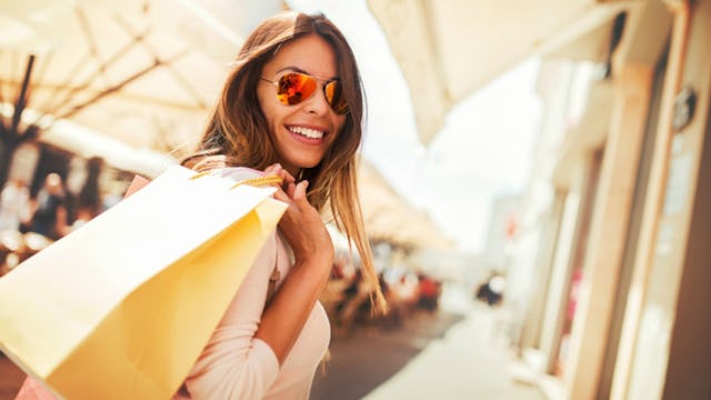 A mother taking time away from her kids for some self-care, holding shopping bags over her shoulder....