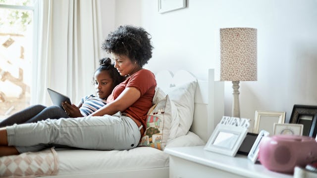 Single mom in a bedroom lying in bed with her daughter