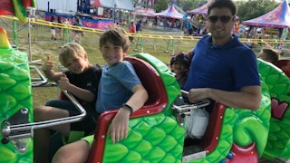 Andrea Smolin's husband and their three children smiling in a roller-coaster