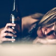 A young blonde girl drunkenly lying with her hair on the table, feeling the shame of alcoholism