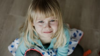 An anxious blonde girl with bangs looking up wearing a mint shirt and a white skirt with large blue ...