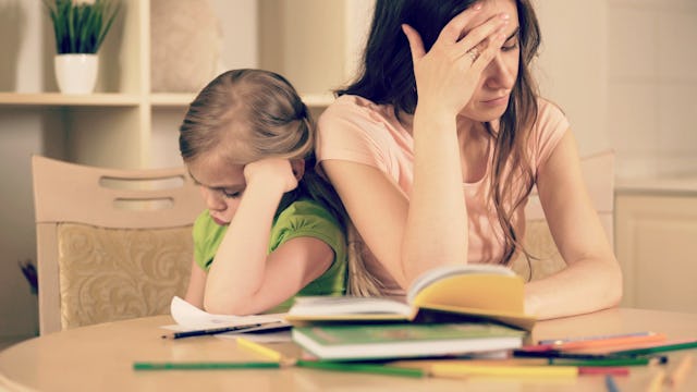 Tired mother helping her mad child with homework