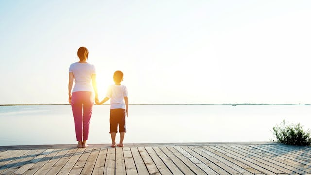 Mother and her son holding hands, looking at the ocean from the coast
