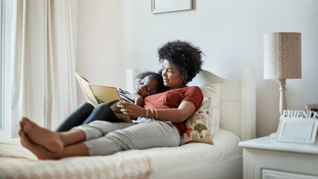 Mom and a girl lying on the bed reading a book.