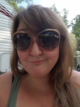 Kira Gilbertson taking a selfie with sunglasses while camping