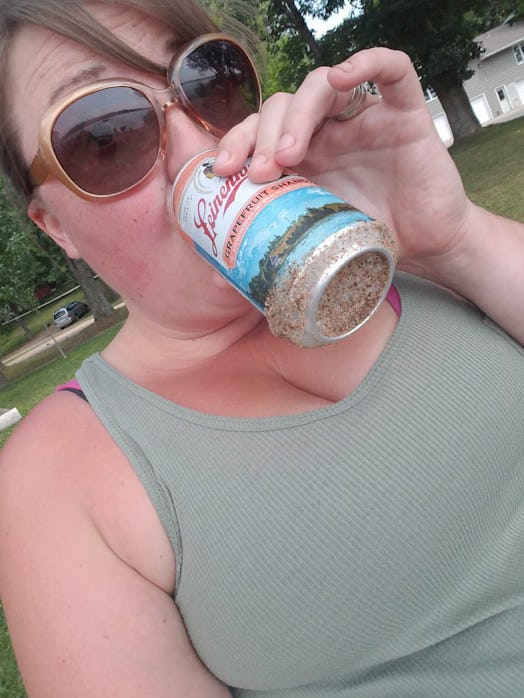 Kira Gilbertson drinking a beer while wearing sunglasses during campring