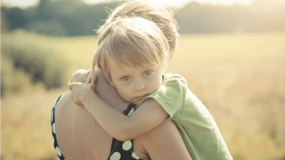 A mother holding her child in her arms on an open field