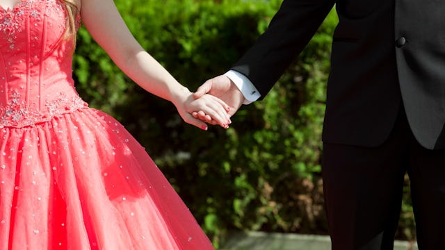 Hand of a boy wearing a black suit and white shirt holding hand of a girl wearing a pink dress, goin...