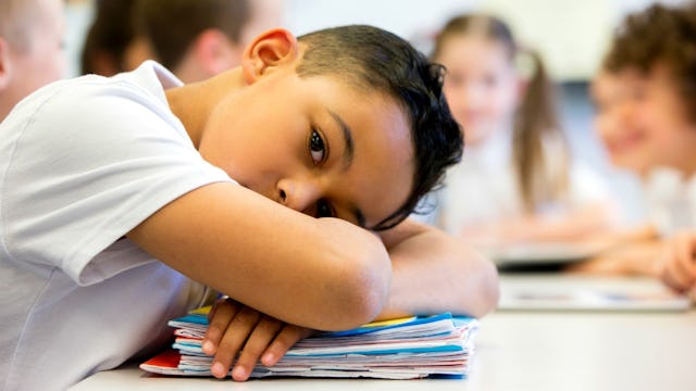 Little boy lying down on his books while struggling with school