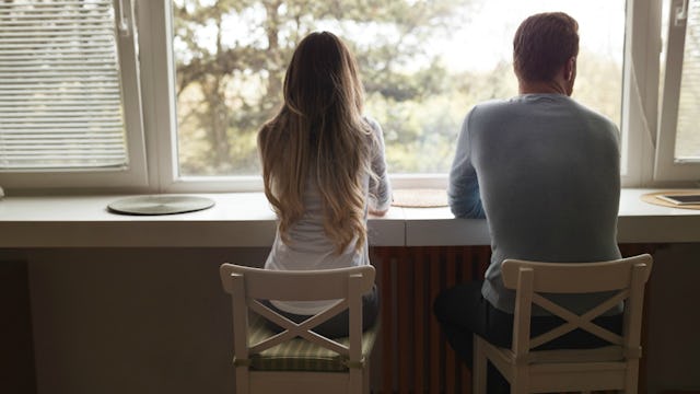 Husband and wife sitting at the window after husband confessed to having an affair
