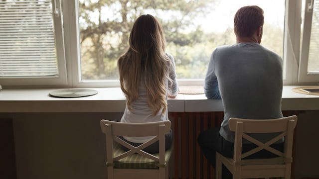 Husband and wife sitting at the window after husband confessed to having an affair 
