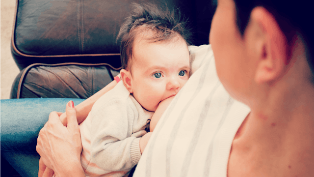 A mom breastfeeding her newborn with blue eyes while looking at it