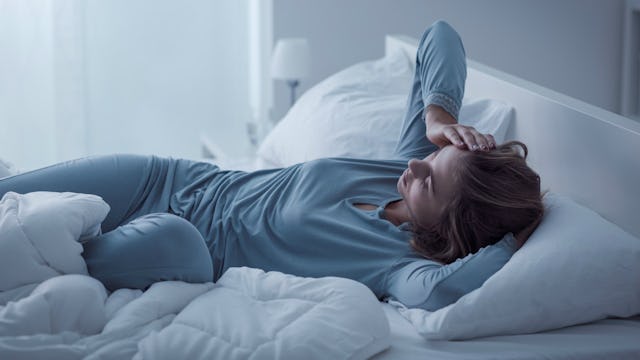 A woman with a mental illness lying in her bed and wearing blue top and pants