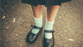 A preschooler's shiny black shoes with white socks 
