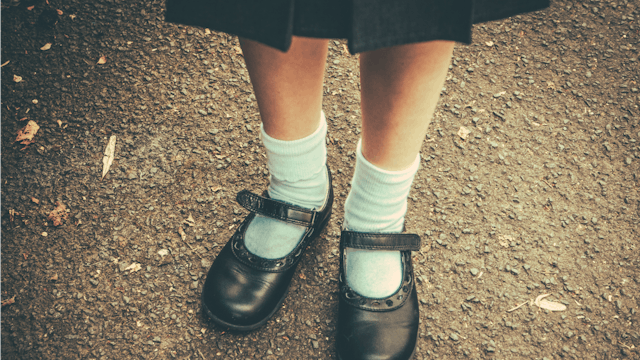 A preschooler's shiny black shoes with white socks 