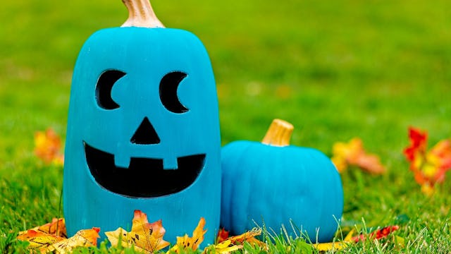 Two teal pumpkin Halloween decorations in a yard that's referring to kids that have allergies.