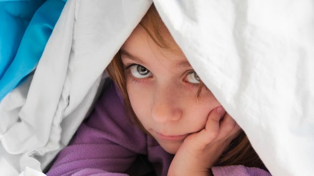 A kid hiding under a blanket, refusing to participate in a birthday party activity 