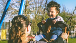 An "older" mom swinging her child in a park 