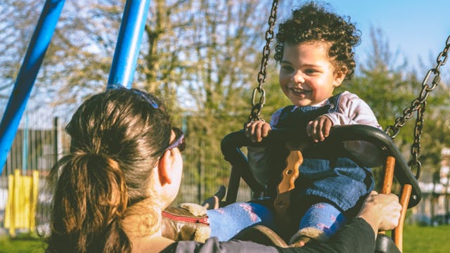 An "older" mom swinging her child in a park