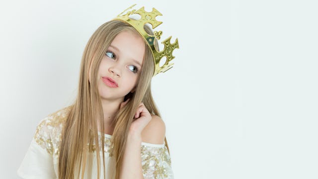 Little blonde girl dressed up in a golden dress with a crown on her head 