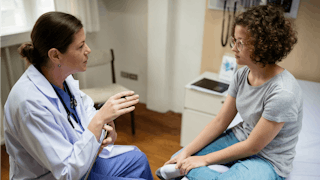 A woman sitting in an ER and speaking to her doctor after she though she was having a heart attack