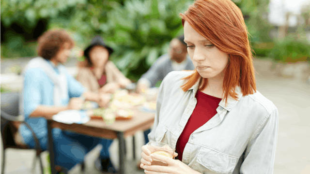 A special needs mom looking worried with a group of people sitting blurred in the background