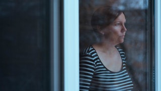 Woman looking through the window because she didn't attend her dad's funeral
