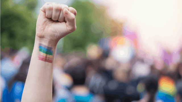 A hand with the LGBTQ+ flag painted on it