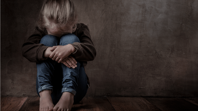 Sad child sitting on the ground and crying