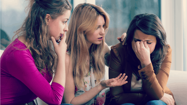 Two girls supporting their friend after a miscarriage