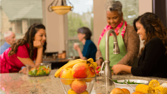 A family hanging out in the kitchen celebrating Thanksgiving on a Saturday.