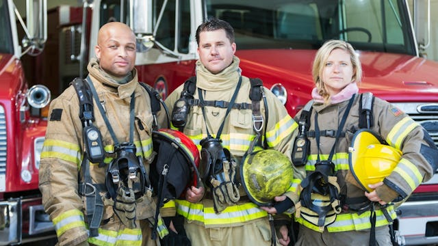 Group of three firefighters on duty in front of a fire truck
