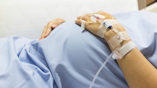 A pregnant woman suffering from Hyperemesis Gravidarum and holding her hands on her belly