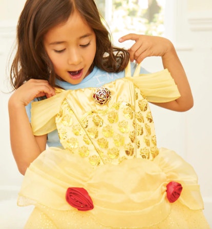 A brunette girl in a blue T-shirt leaning a yellow Belle dress on her 