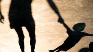 Shadow of a parent holding a shadow of it's child by the hand on a yellow surface