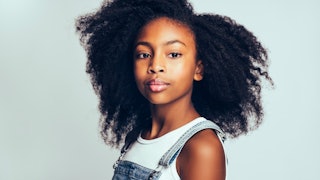 A teenage girl with black curly afro hair in a white top
