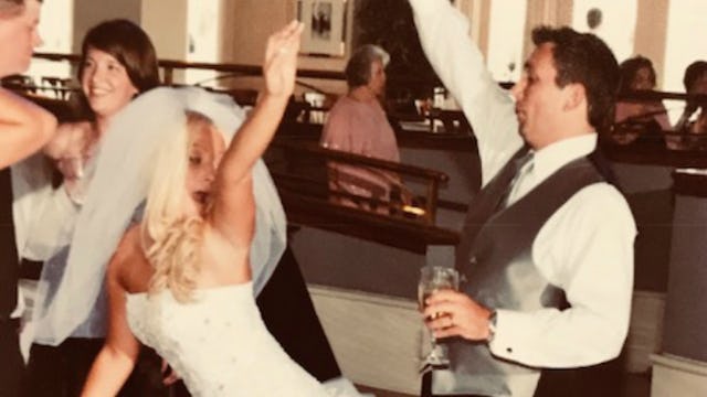 A bride and a groom dancing with friends at their wedding