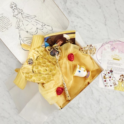 An open Disney Princess subscription box with a visible yellow Belle dress and other accessories