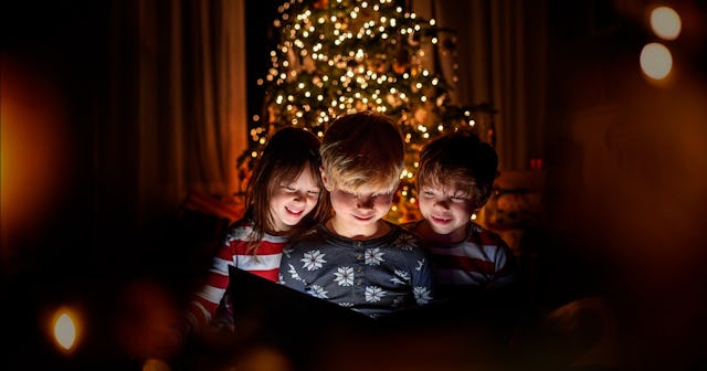 Children reading in front of Christmas tree — Christmas Eve traditions