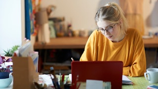 A girl sitting in a kitchen writing pornographic fanfic 