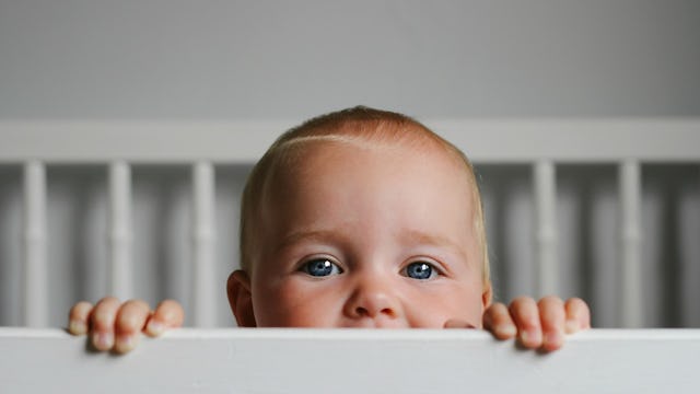 A baby boy peeking out of his crib and a mother refusing to change his sleep schedule for events
