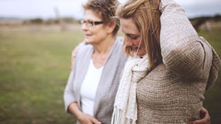 A mother and her grown up daughter hugging and walking